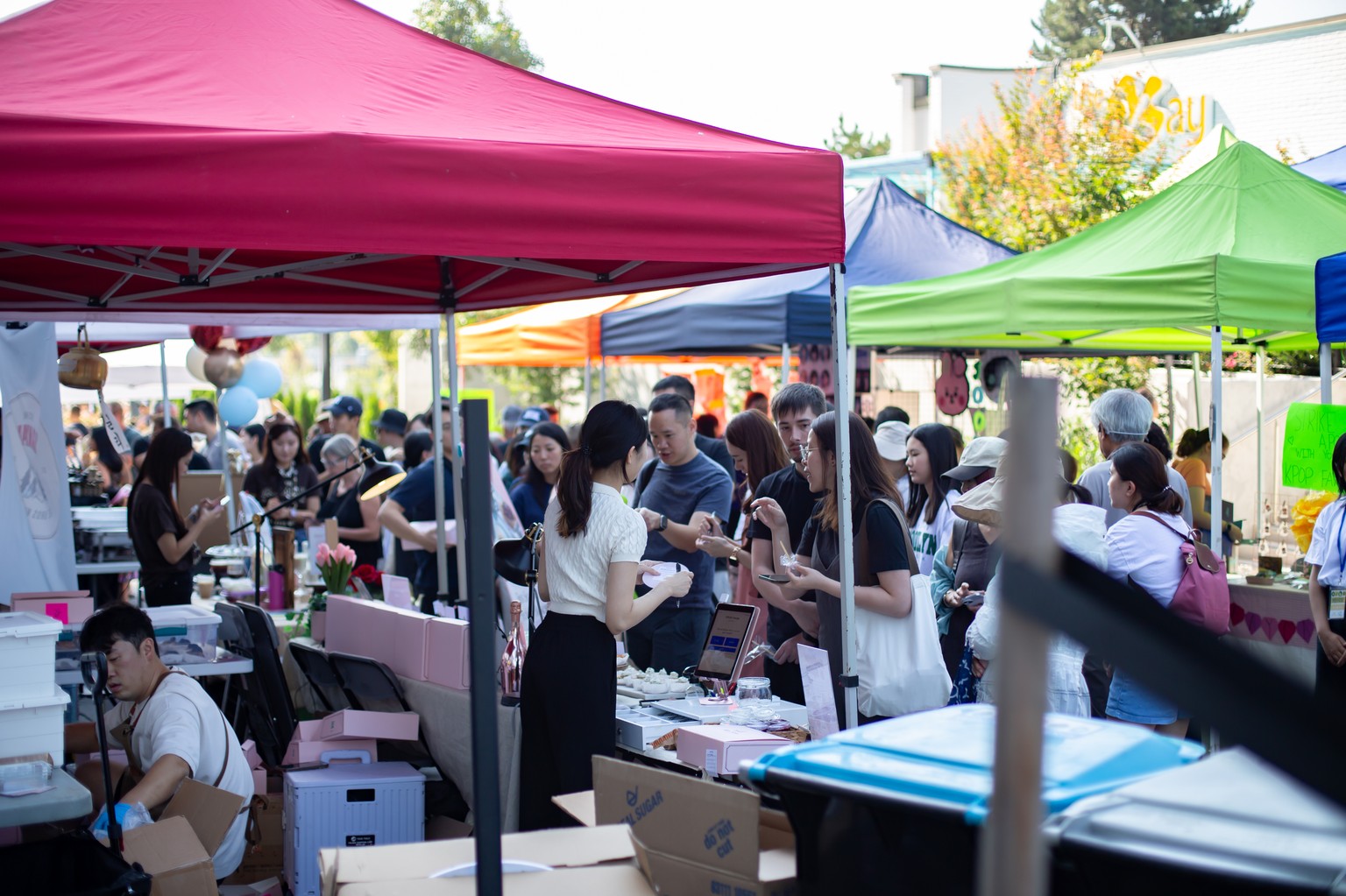 A busy community market beneath rows of colourful vendor tents