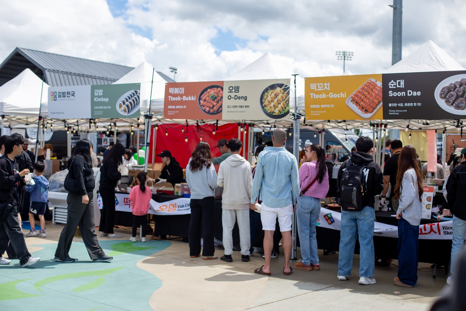 A busy K-Food Festival market with visitors lining up at Korean food booths
