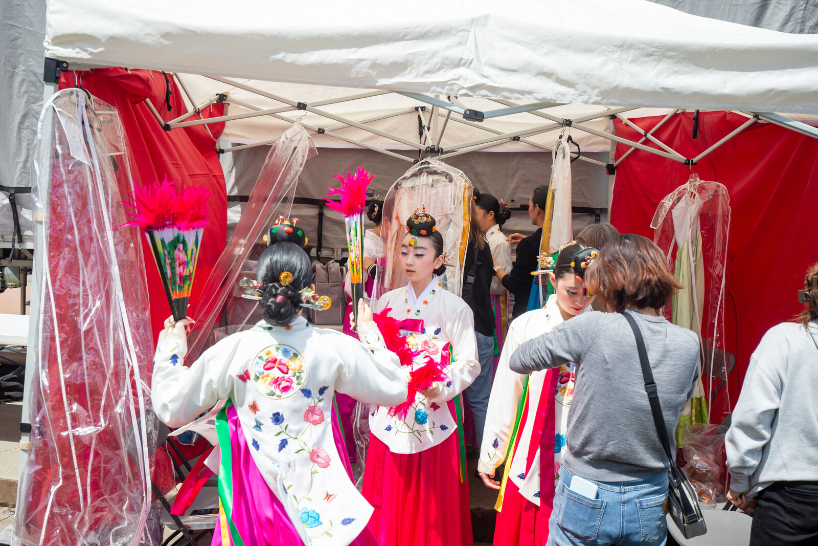 Performers wearing colourful Korean hanbok preparing beside the stage